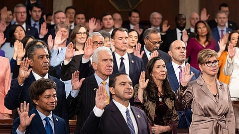 Many members of the U.S. House of Representatives stand with their hands up in oath.