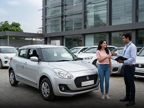 A woman takes keys from a slaesman with binder, standing next to a car
