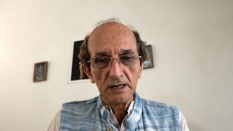 In the image Prof. Michel Danino is shown behind him is three photo frames he is wearing Indian outfit with glasses