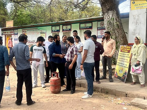 A group of people standing near a gas agency to recieve their cylinders.