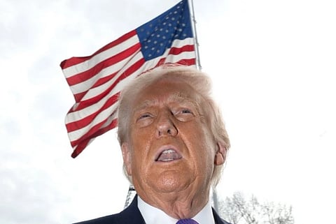 Closeup photograph of Donald Trump. Behind him the national flag of united states is visible.