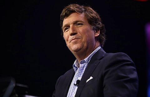 Image of Tucker Carlson, a political commentator. in the image the background of the subject is dark and poorly lit. Carlson speaking with attendees at the 2023 Turning Point Action Conference at the Palm Beach County Convention Center in West Palm Beach, Florida.