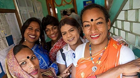 In the image five members of Hijra community are shown dressing in colourful clothes smiling at the camera