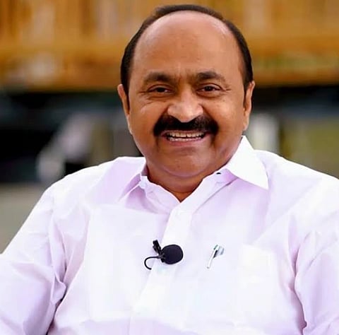 Image of 11th leader of opposition Vd Satheesan in a white shirt and a label mic attached to it.. the background is blurred.