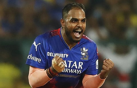 image of Yash Dayal in a blue and red jersey celebrates on the field, gesturing with intensity. The blurred crowd in the background adds to the energetic atmosphere.