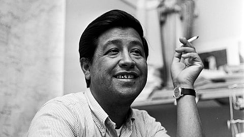 The image shows Cesar Chavez, a farm union leader, holding a cigarette and smiling