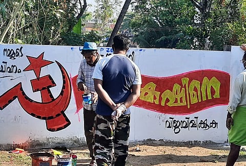 Kerala Assembly election 2026|Image of Kerala Election campaign 2021 Graffiti. Men in the image are painting the CPM logo on the wall.