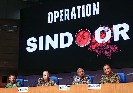 Image of army personnels sitting behind a wooden panel. Behind them is a huge digital screen on which operation sindoor is written