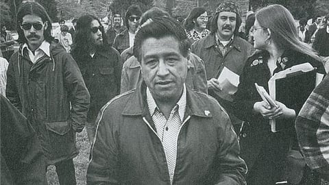 The image shows United Farm Workers co-founder Cesar Chavez, walking among a crowd.