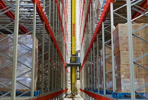 a mechanical device between two shelves in a warehouse full of boxes