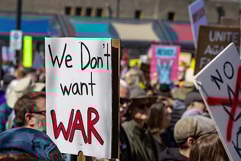 A psoter reading "we don't want war" with a crowd in the background