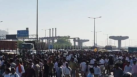 A large crowd in front of a highway in Noida