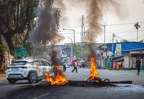 Bishnupur: Protesters burn tyres and place stones on the road near Bishnupur District Hospital to block the movement of security forces during clashes in Thinungei, Bishnupur district of Manipur on Tuesday, April 14, 2026.