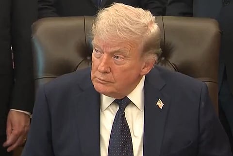 Image of President Donald trump looking sideways in a serious expression. three men stands behind him.