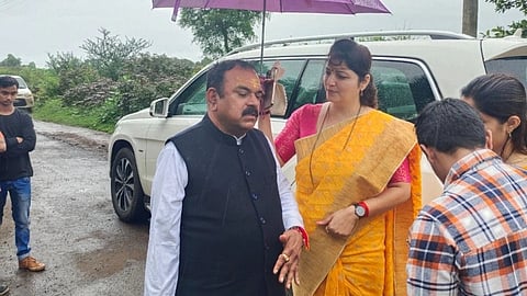 Ashok Kharat stands under an umbrella held by Rupali Chakankar.