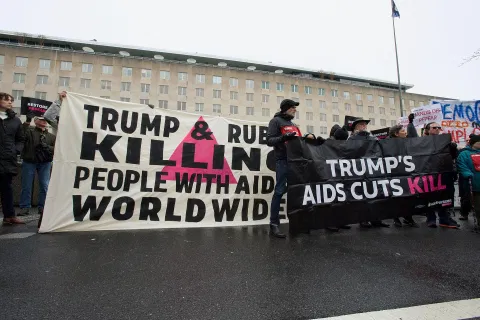 Group holding up two banners saying Trump is killing people with HIV aid cuts
