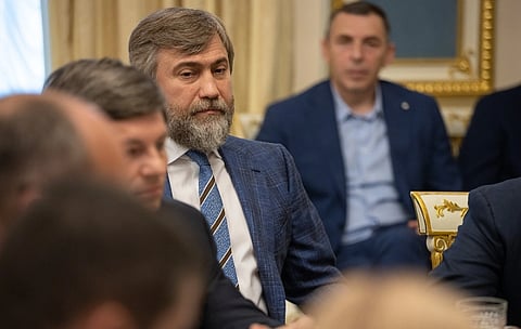 Image of billionaire former lawmaker Vadym Novynskiy in a blue suit, he is seated in a room full of people.