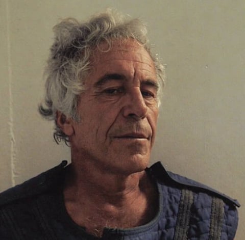 Image of jeffrey Epstein smiling and looking slightly downwards. He is wearing blue half sleeved jacket.
