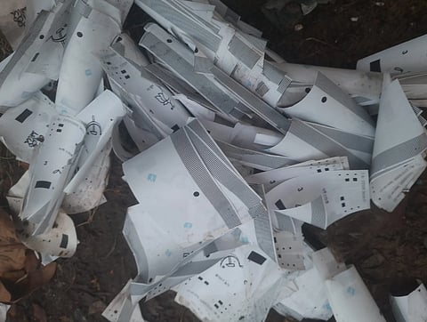 West Bengal Assembly election 2026| A pile of crumpled white papers with various black printed symbols and lines, scattered on soil, conveying a sense of disarray and neglect.