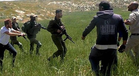 Armed Israeli settler accompanied by soldiers threatens Palestinian farmers near a-Tuwani, South Hebron Hills