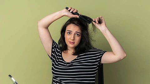 woman curling her hair with a brush