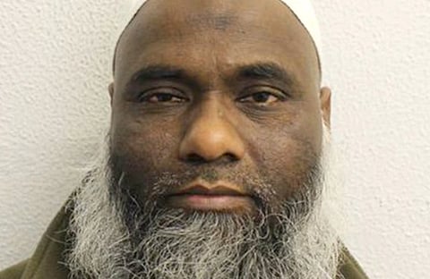 Elderly man with a white beard and wearing a white cap, looking directly at the camera against a plain, light-colored background. Neutral expression.