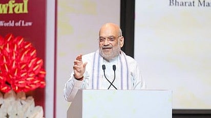 In the image Amit Shah is shown speaking in a formal event in a podium