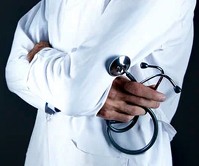 A doctor is standing and holding a stethoscope, handling patients.