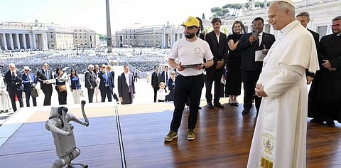 A small robot performs on a wooden stage in front of an audience, with a man in casual clothes and a hat controlling it, while religious and official figures, including a person in white robes observing with interest, stand nearby. The mood is a mix of curiosity and amusement.