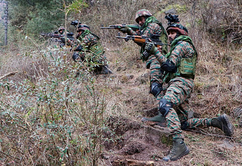 Four Army officers in a grass covered area with guns
