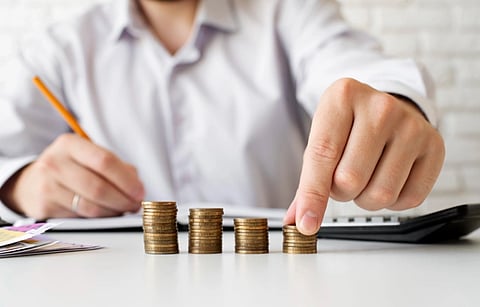 Image of a man writing and managing his finances. he is seated in front of pages and is seen holding a pen in his right hand.