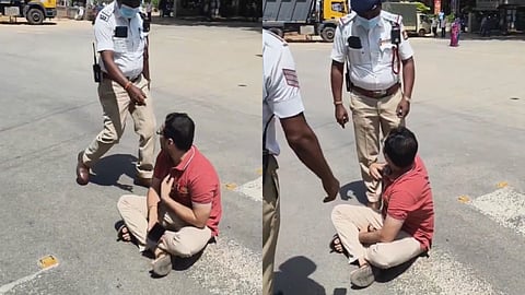 Bengaluru man sitting on a busy road surrounded by police officers while protesting traffic restrictions caused by a VIP convoy