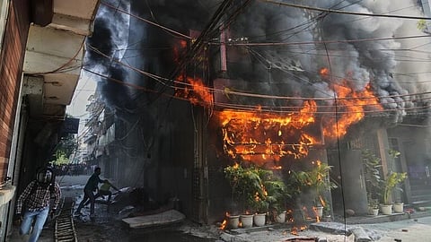 Flames consume a building in Malviya Nagar, India, as smoke billows into the air during a fire incident.