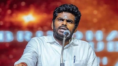 In the image K Annamalai is shown addressing the people behind him is a golden screen