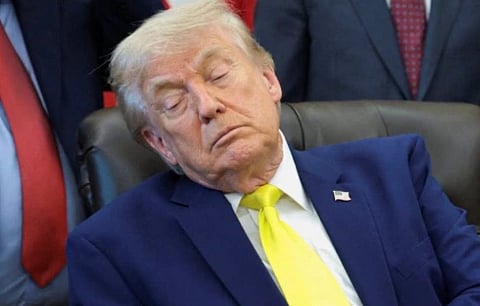 Image of Donald Trump in a blue suit and yellow tie sits in a chair with his eyes closed, conveying a sense of exhaustion. Others in suits are seen in the background.