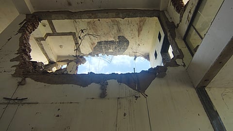 In the image a big hole in a wall is shown which is cause by the Air India plane crash