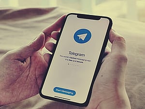an image of a hand cradling a phone, with the logo of the telegram app displayed