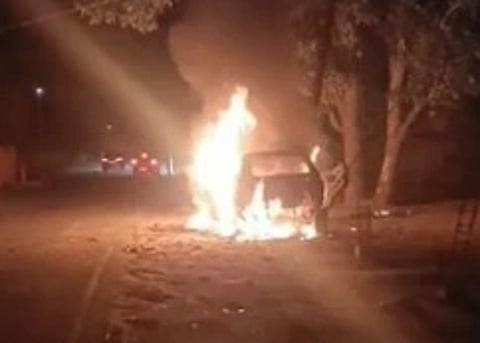 image of a car on fire. the image is dimly lit and pixelated.