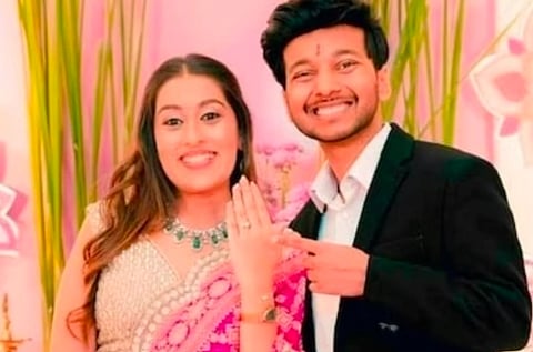Image of Siya Goyal and Ketan Agarwal. the couple are engaged in the image and Siya is holding her left hand up showing her engagement ring. The image has a pinkish tone to it.