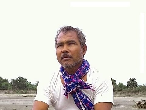 Image of Jadav Payeng sitting witha blue sloth tied around his neck.
