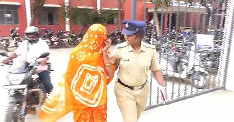 In the image a women is shown hiding her face with a police officer