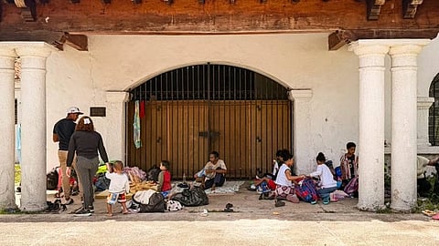 A group of children, rest under an archway with white pillars, surrounded by bags in Venezuela following earthquake