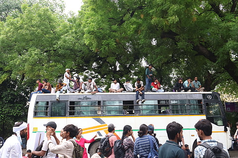 Image from CJP March on July 20, 2026. in the image and several people can be seen sitting at the top of a bus and many people are also standing at the ground near the bus.