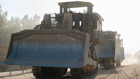 A powerful Israeli Military bulldozer with a wide blade, positioned on a dirt surface, ready for earth-moving tasks.