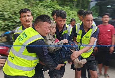 In the image many resuers are shown rescuing a old lady lost during the Nepal flood