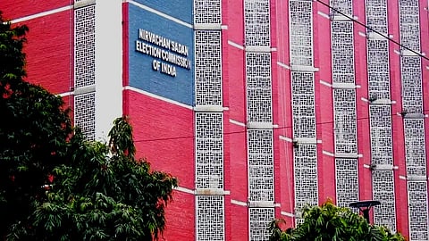 A red building with some trees in the foreground.