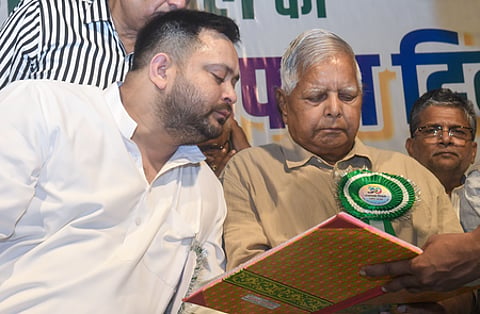 Image of Lalu and Yadav and his son Tejaswi yadav looking at a diary