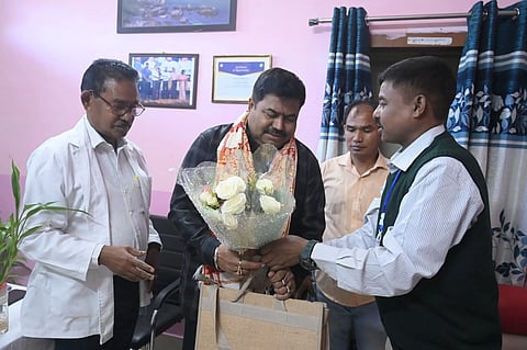 A group of men felicitating another man with a bouquet.
