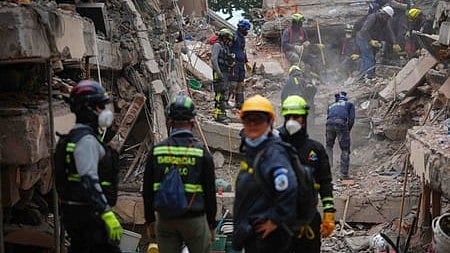Rescue workers in helmets and masks search through a collapsed building’s rubble, conveying urgency, teamwork, and hope after a disaster.