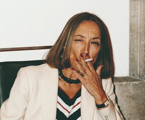 Image of Italian journalist Oriana Fallaci smoking a cigarette in a white suit.